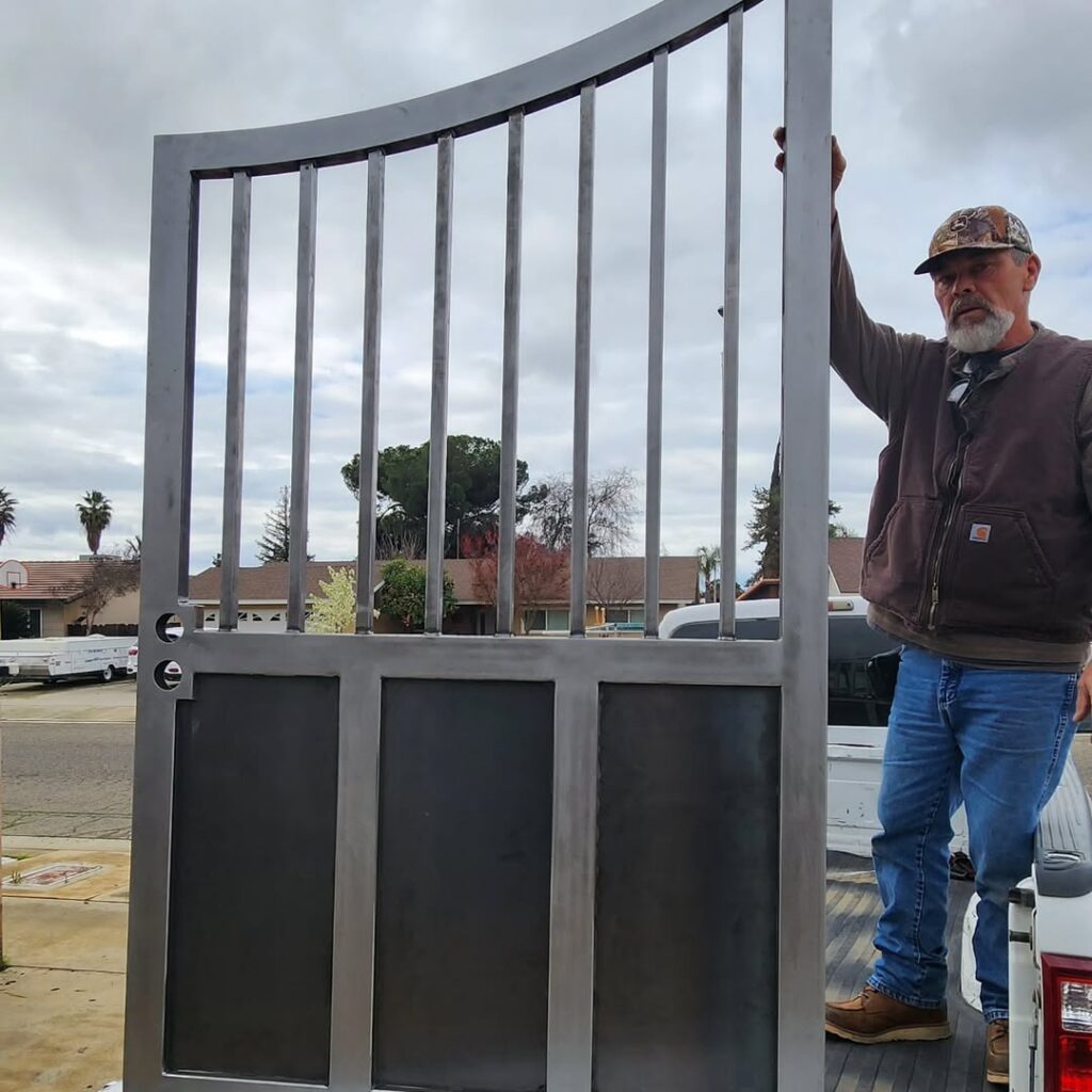 Completed steel driveway gate with a crew member on site